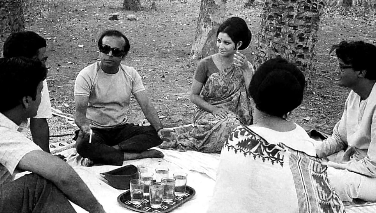 Film still: friends picnicking on the forest floor