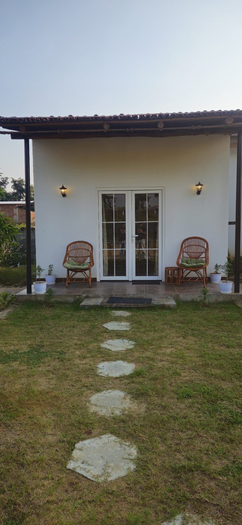 White cottage veranda with two cane chairs facing the lawn