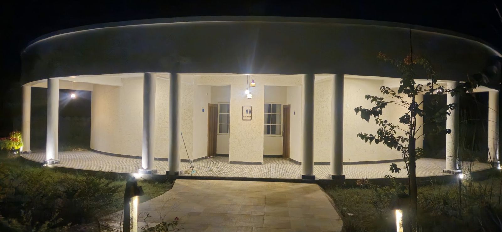 Colonnaded white cottage lit at night