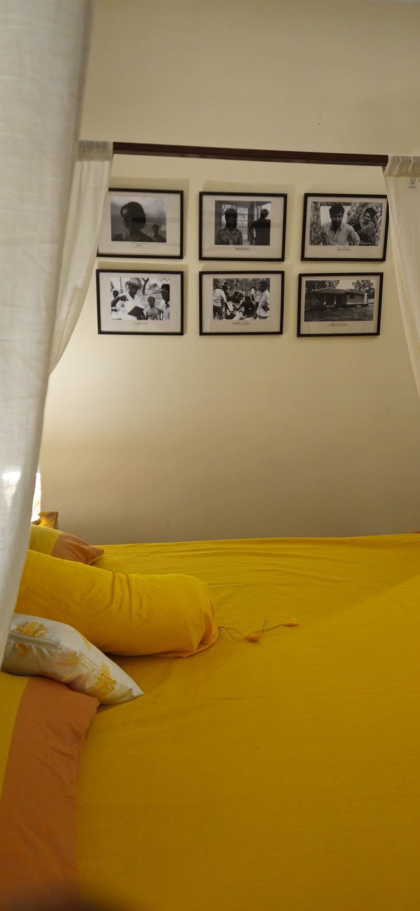 Bed with saffron linen beneath framed Palamu engravings